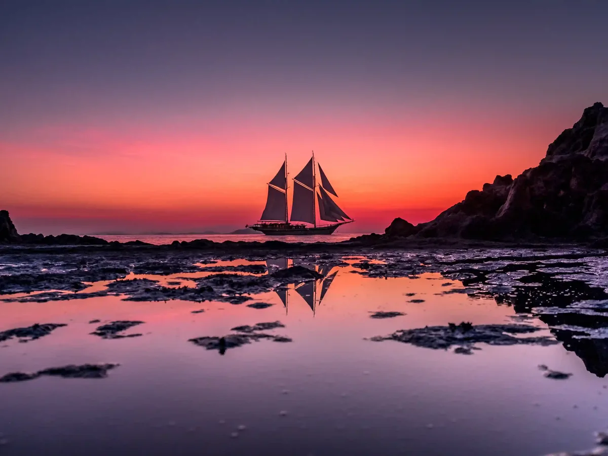 A phinisi under sail in golden evening light