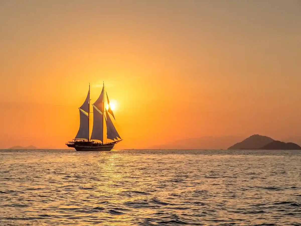 A phinisi silhouetted against the sunset